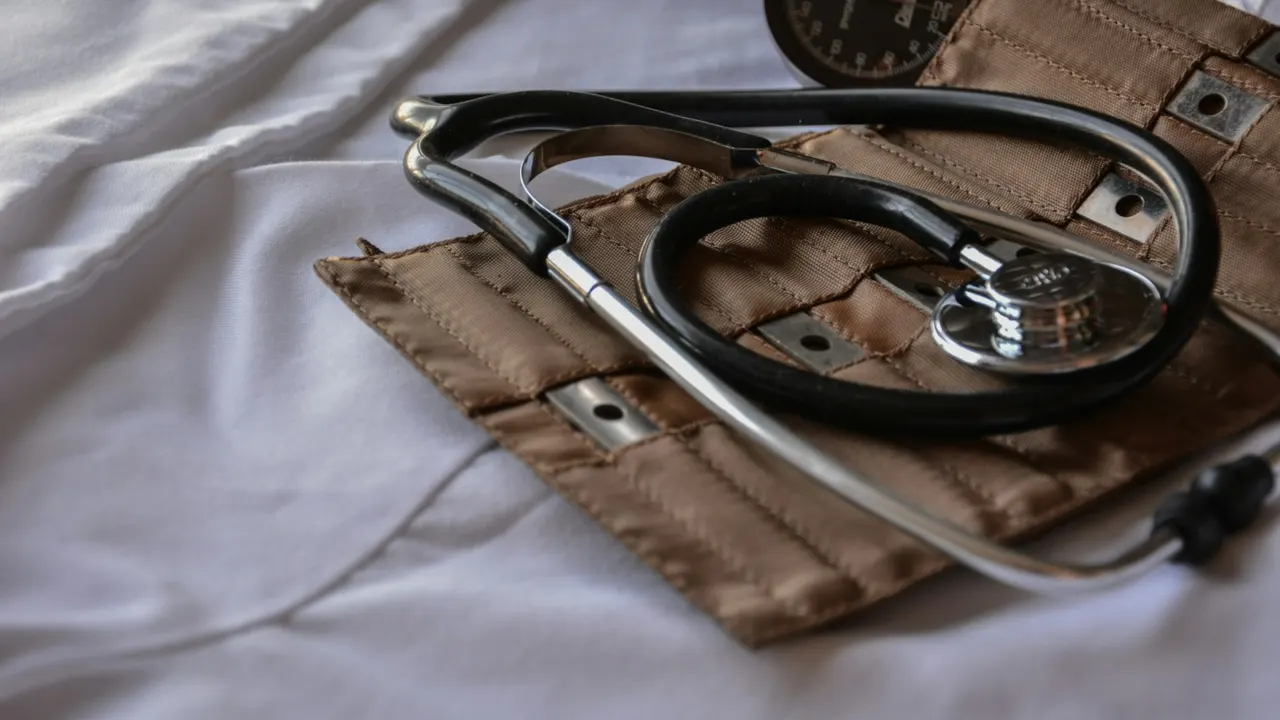 Black stethoscope resting on a brown leather case on a white sheet