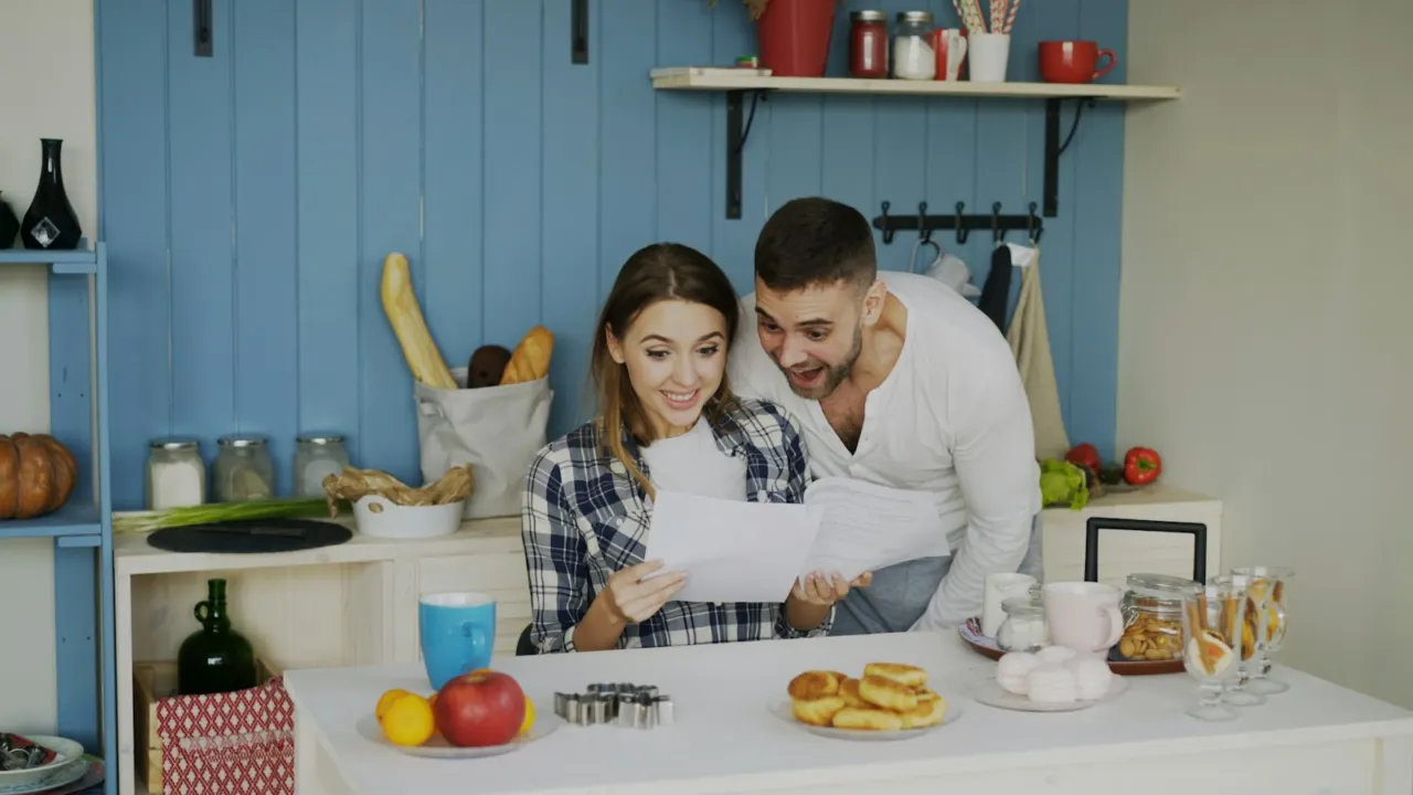 Couple reading printed papers together at a bright kitchen counter