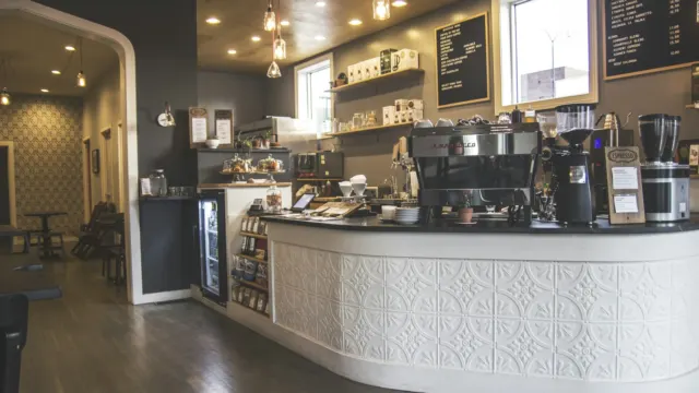 A bright café counter with espresso machines and a chalkboard menu behind it