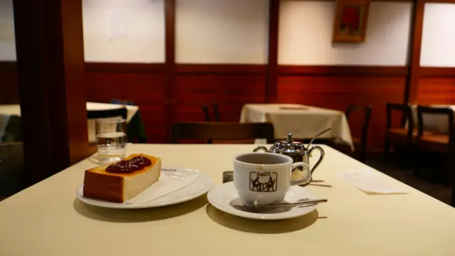 A slice of cake and a cup of coffee on a white tablecloth in a quiet café