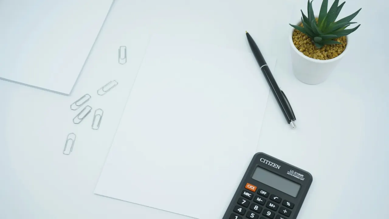 Black calculator and pen resting on printed financial papers