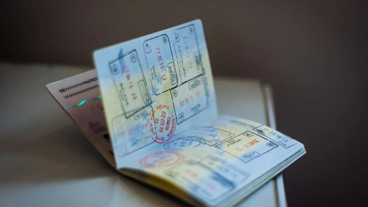Open passport with colourful entry stamps lying on a table