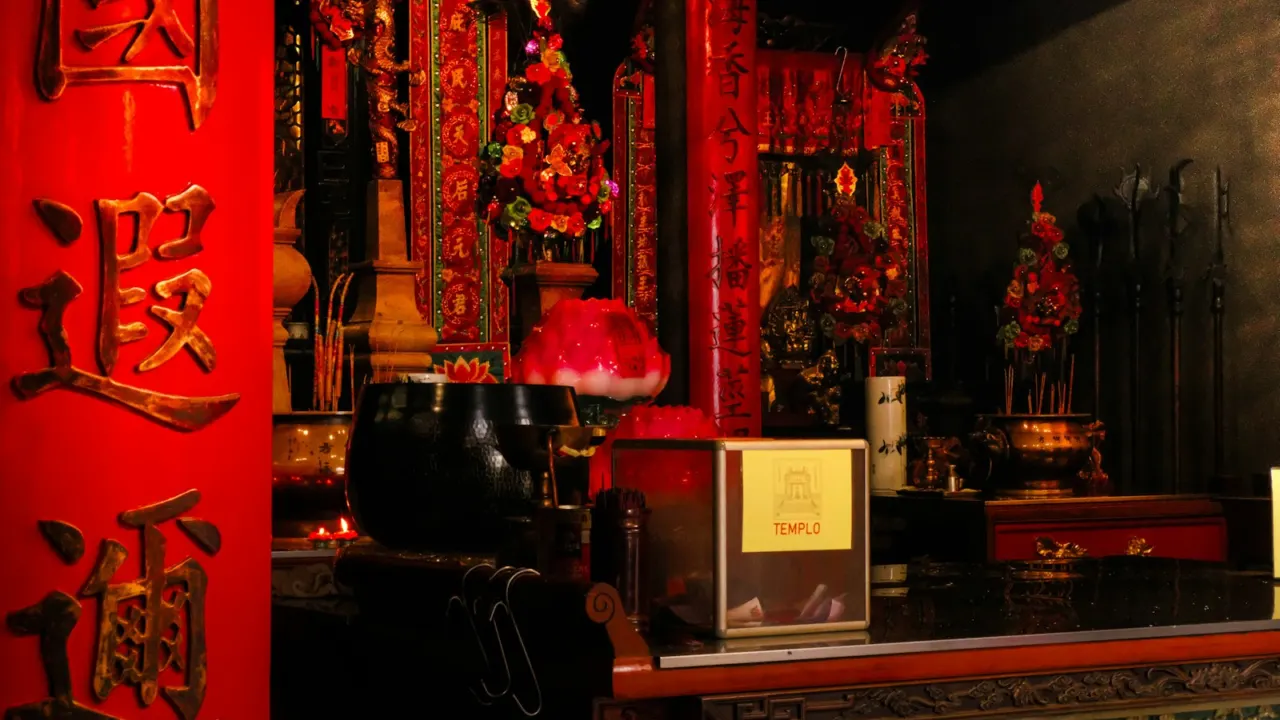 Temple altar decorated in red and gold with Chinese calligraphy on a red pillar