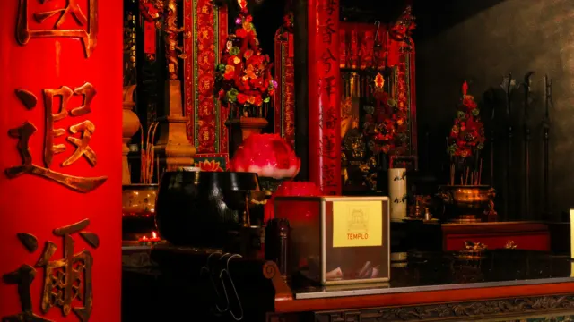 Temple altar decorated in red and gold with Chinese calligraphy on a red pillar