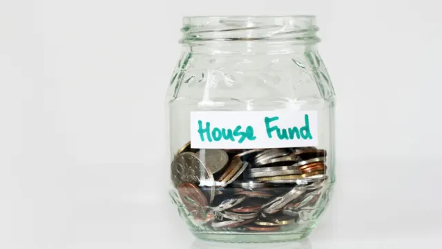 Coins in a clear glass jar labelled house fund