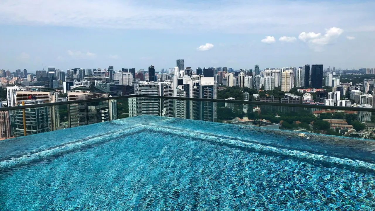 Rooftop infinity pool on a condominium overlooking Singapore high-rise buildings on a sunny day