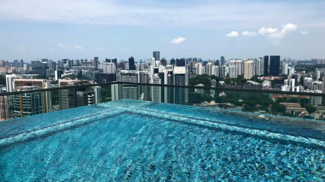 Rooftop infinity pool on a condominium overlooking Singapore high-rise buildings on a sunny day