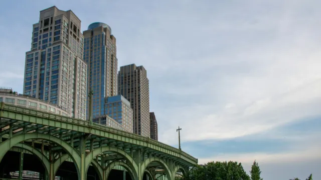 Train crossing a green steel viaduct beside tall residential towers