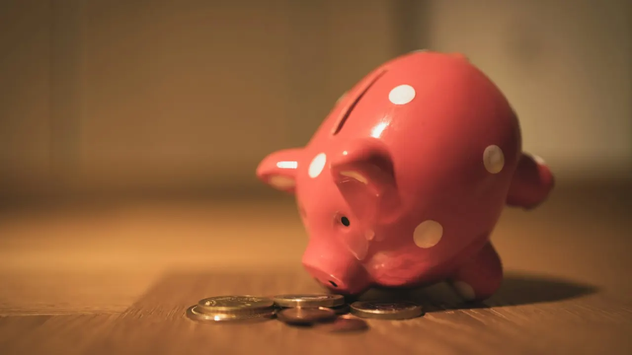 Pink piggy bank standing on a brown wooden table