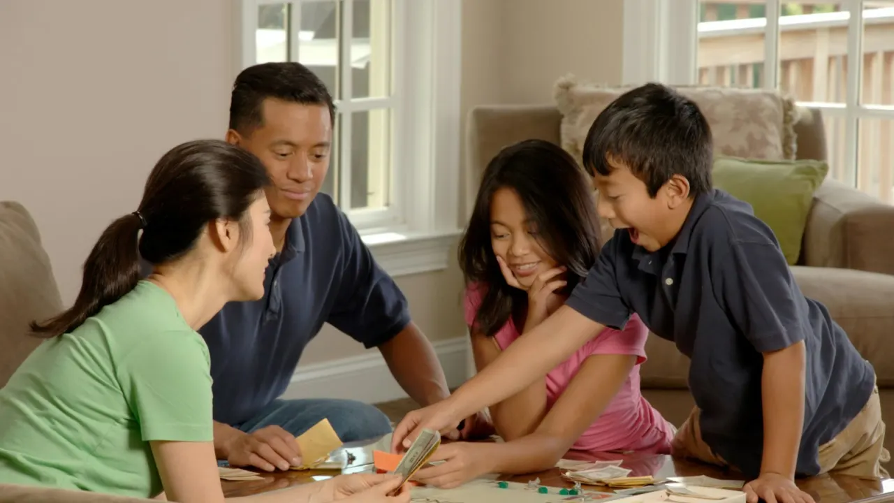 Three-generation family playing a board game together in a bright living room