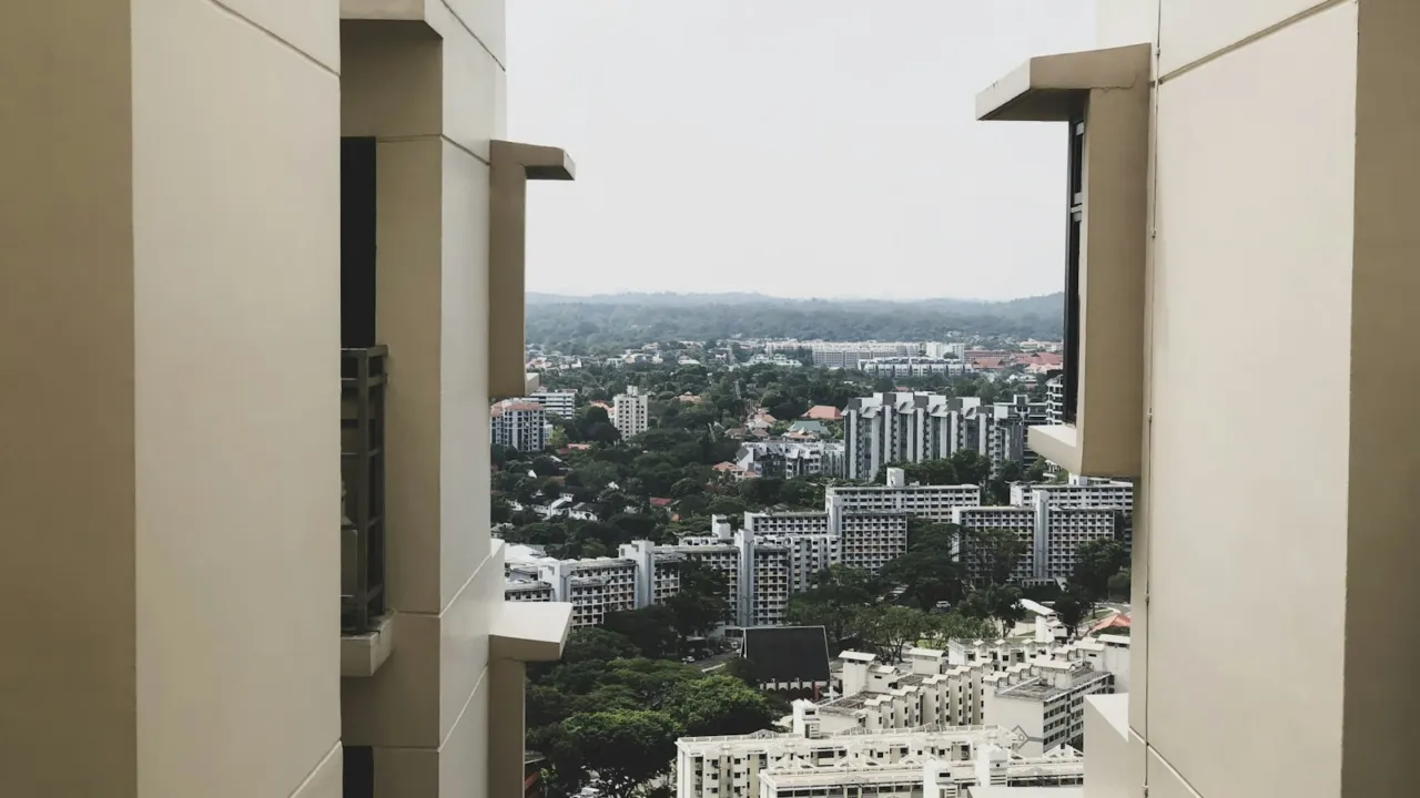 View between two high-rise residential blocks over a Singapore housing estate with trees and low-rise buildings