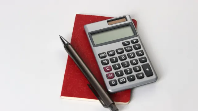 Black and silver calculator next to a black pen on a desk