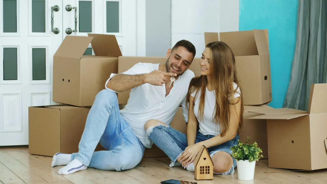 Couple sitting on the floor among cardboard moving boxes in a new home