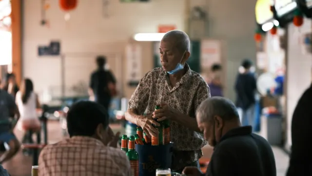 Older men sharing drinks at a table in a busy Singapore coffee shop
