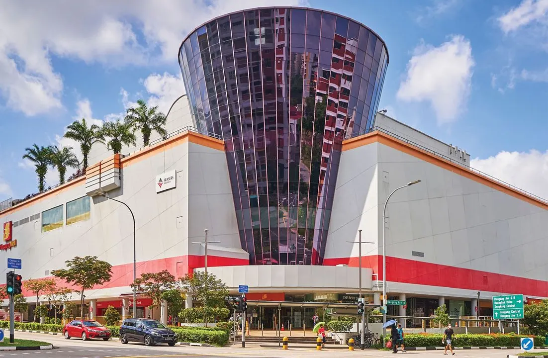 Hougang Mall’s glass-fronted entrance tower on Hougang Avenue 10 under a blue sky