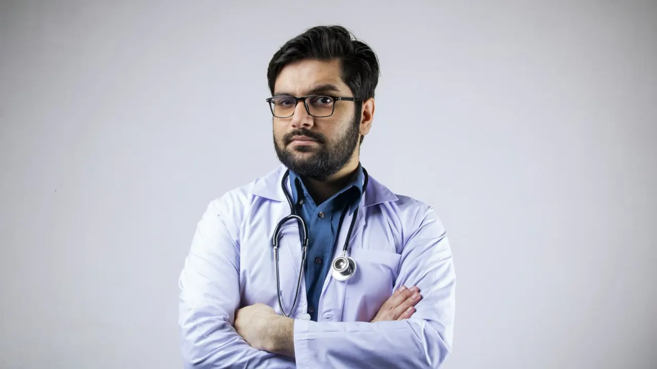 Doctor in a white coat with a stethoscope around his neck, arms folded