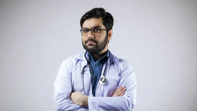 Doctor in a white coat with a stethoscope around his neck, arms folded
