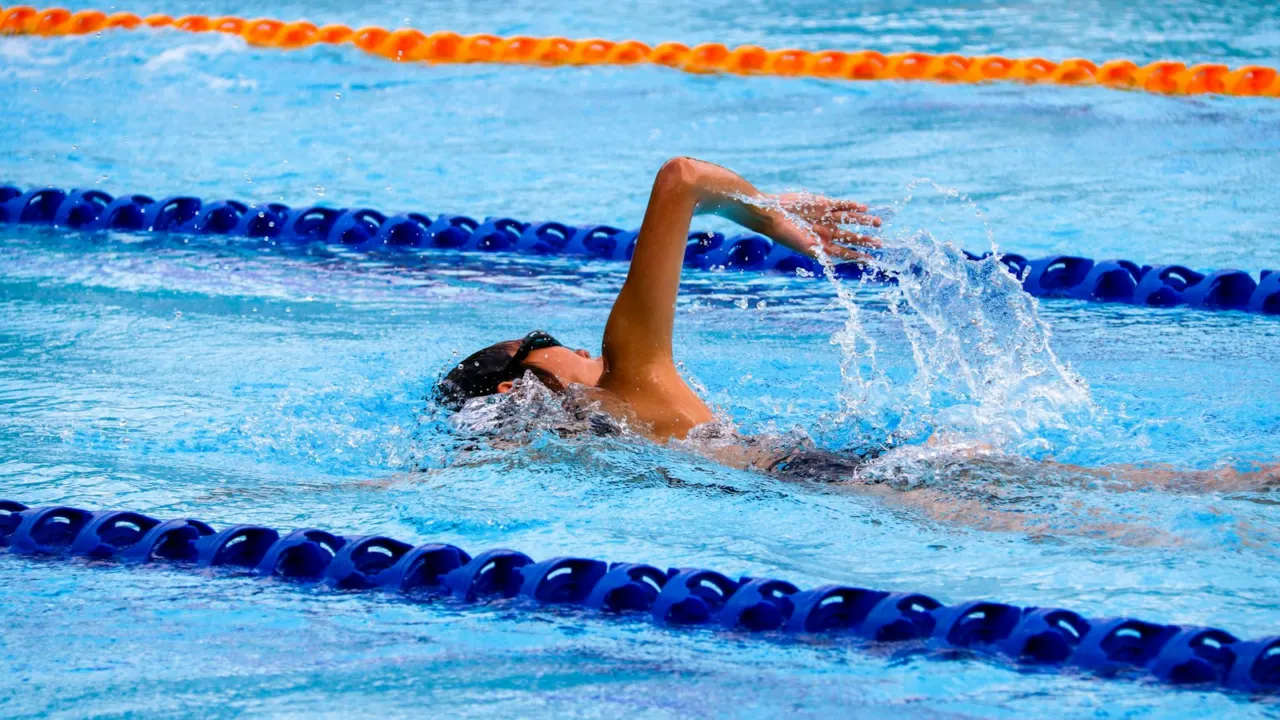 Swimmer doing freestyle between blue lane ropes in a pool