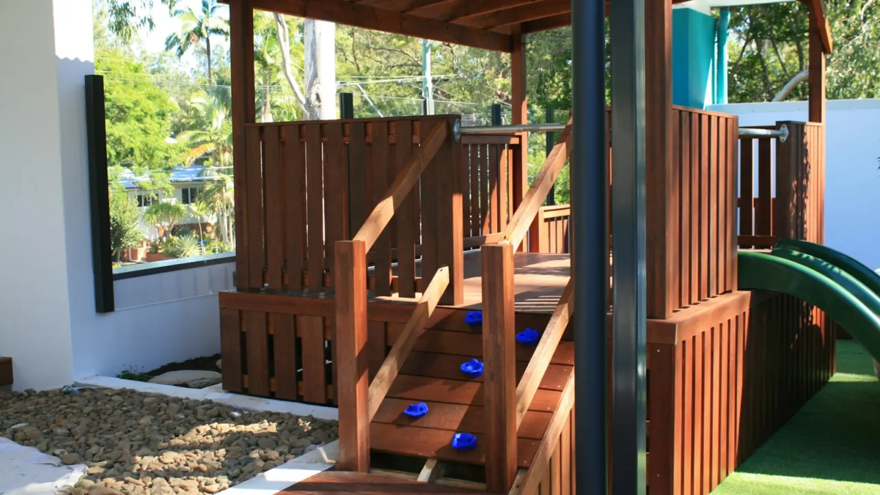 Wooden children’s play structure with steps, railings and a green slide