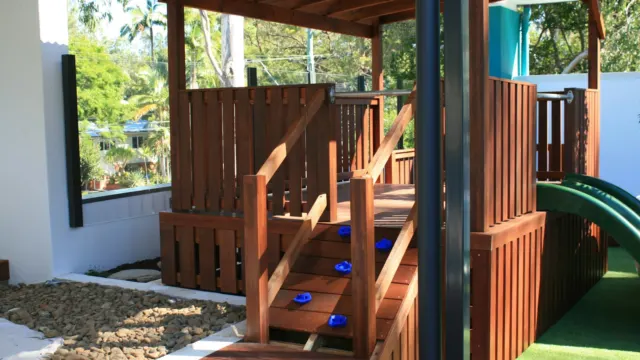 Wooden children’s play structure with steps, railings and a green slide