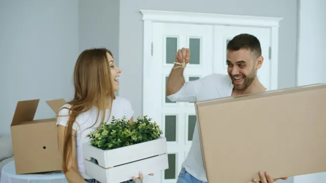 Smiling couple carrying moving boxes into their new home