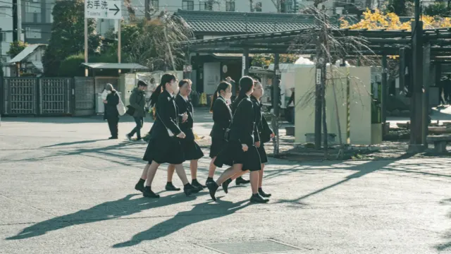 Two schoolgirls in uniform walking together along a pavement