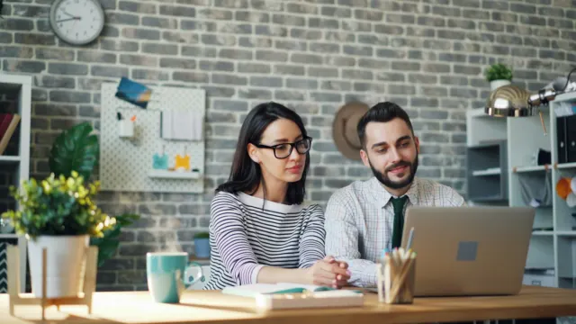 Man and woman sitting at a table looking at a laptop together