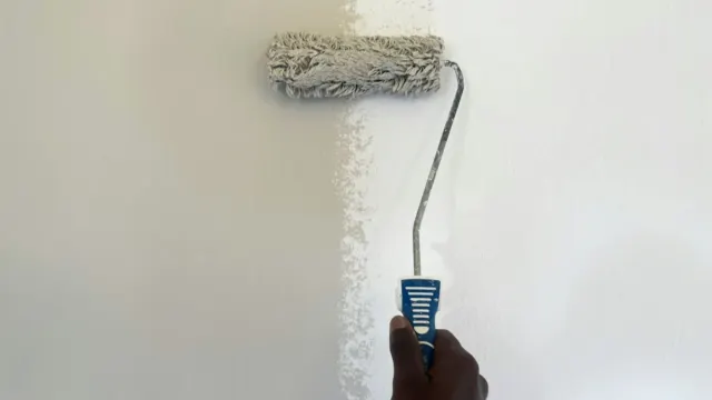 Paint roller applying white paint to a bare interior wall