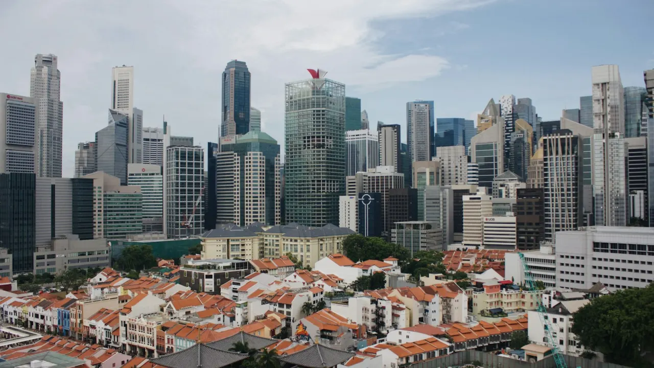 Low-rise houses with red roofs in front of a cluster of high-rise towers in Singapore