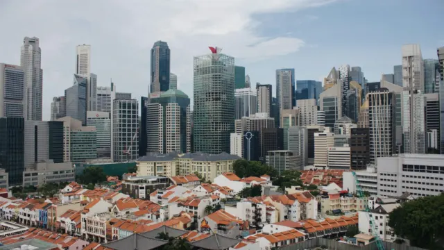 Low-rise houses with red roofs in front of a cluster of high-rise towers in Singapore