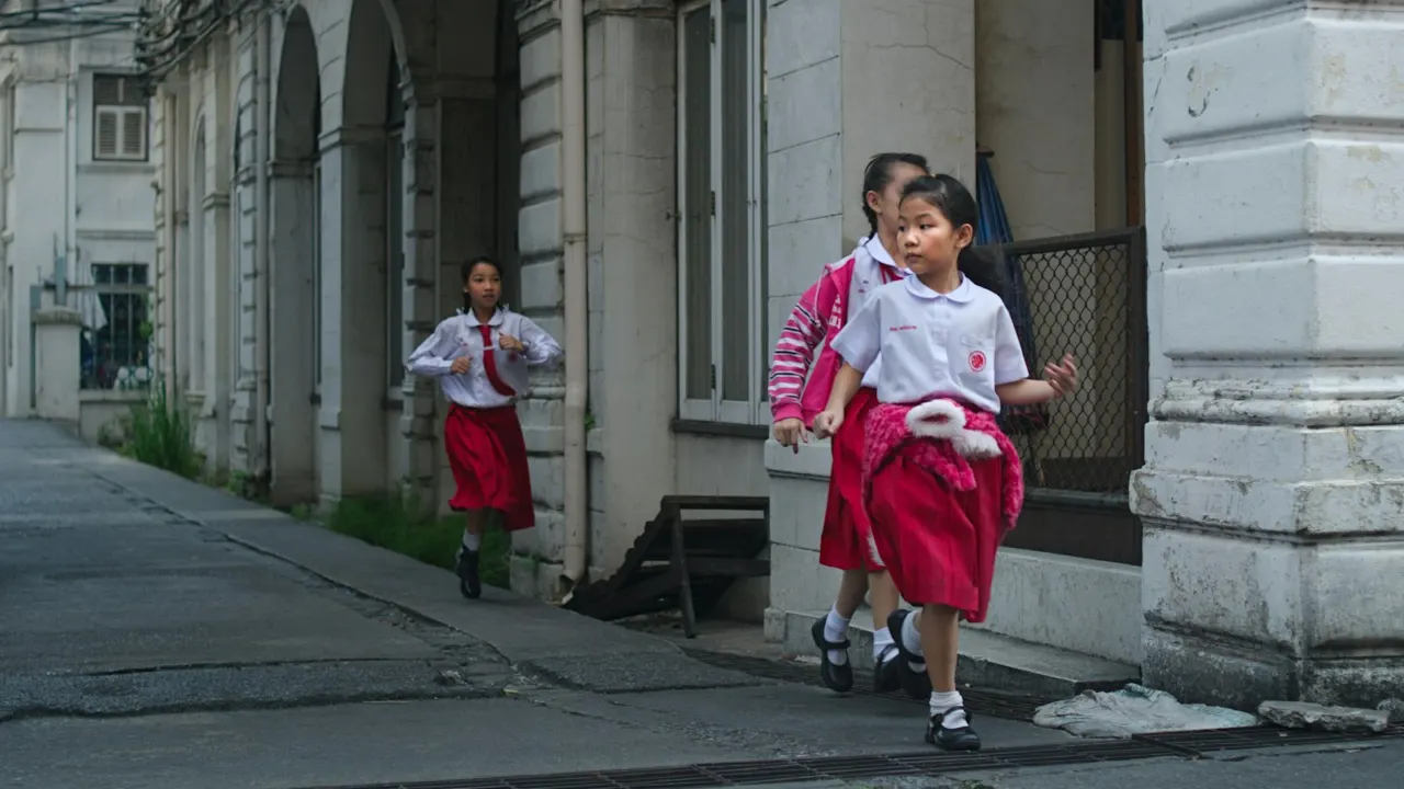 Two young schoolgirls in red and white uniforms walking along a covered walkway