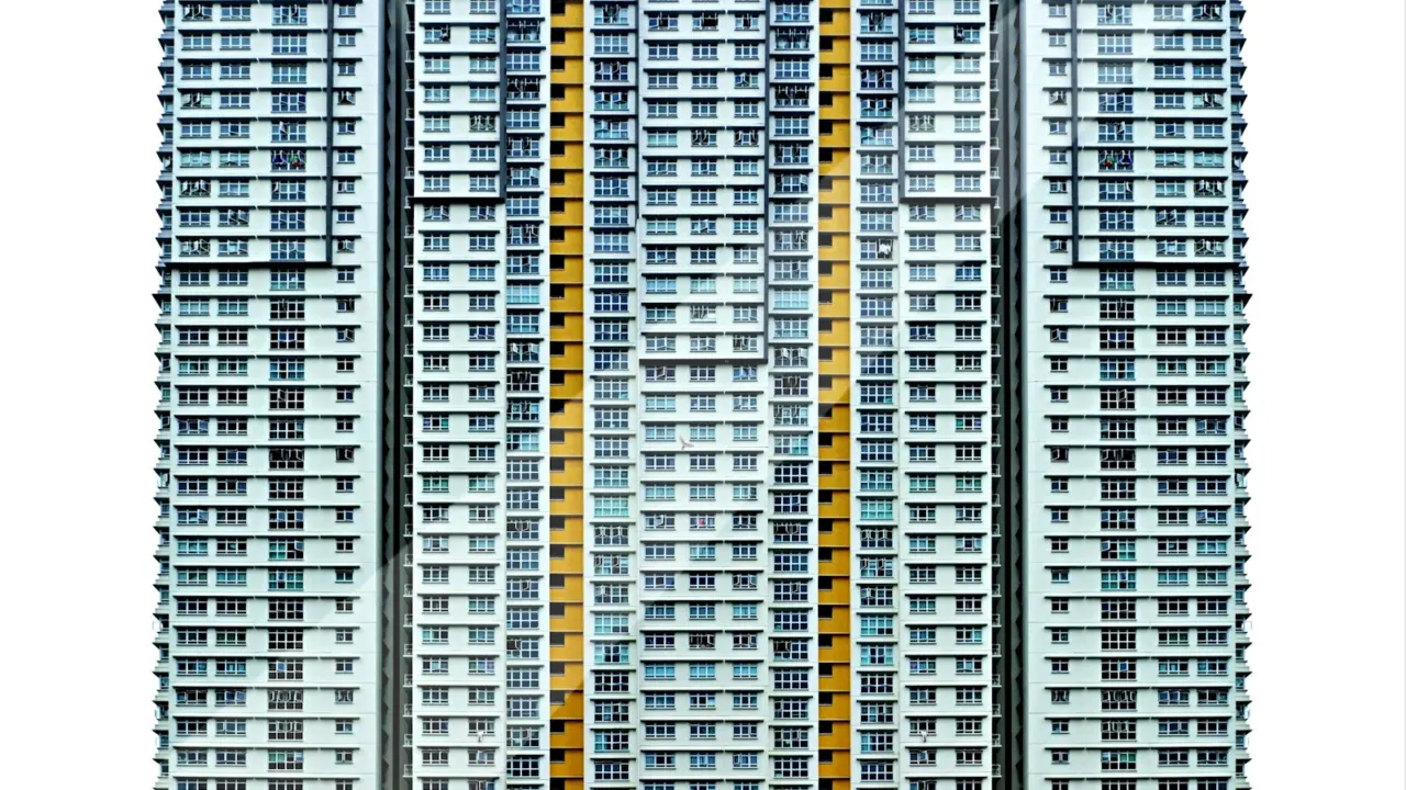 Tall residential tower block with many windows against a white sky