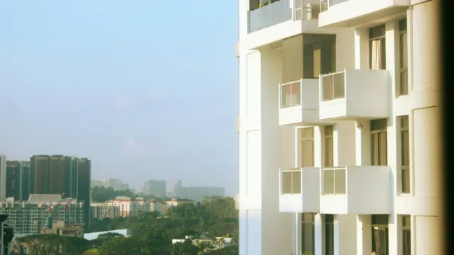White condominium tower with stacked balconies against a clear sky