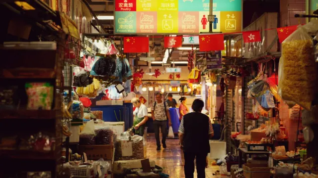 Busy indoor market lane lined with stalls selling household goods and produce