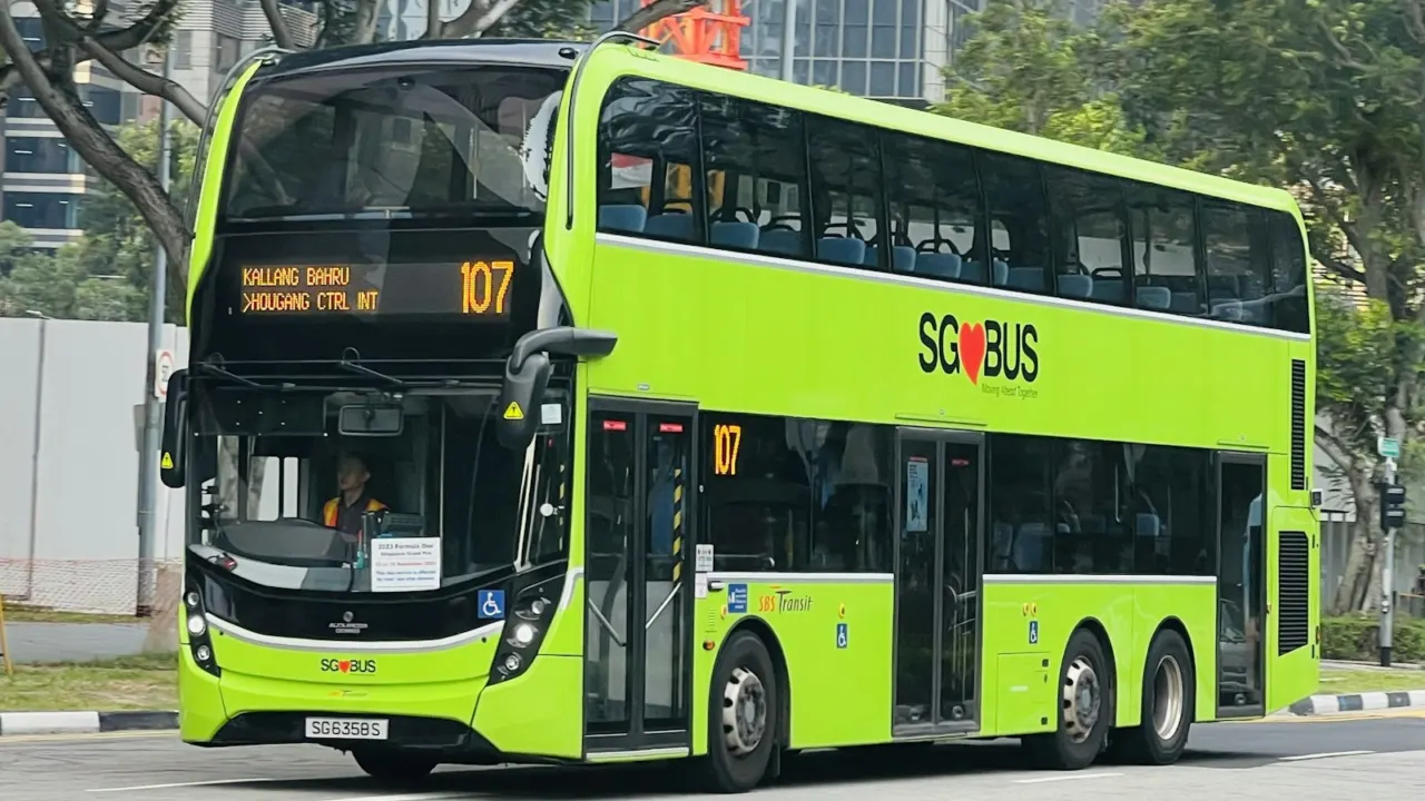 Green double-decker public bus driving along a road