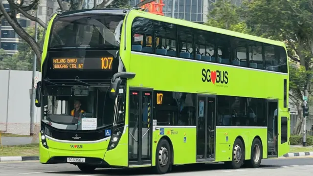 Green double-decker public bus driving along a road
