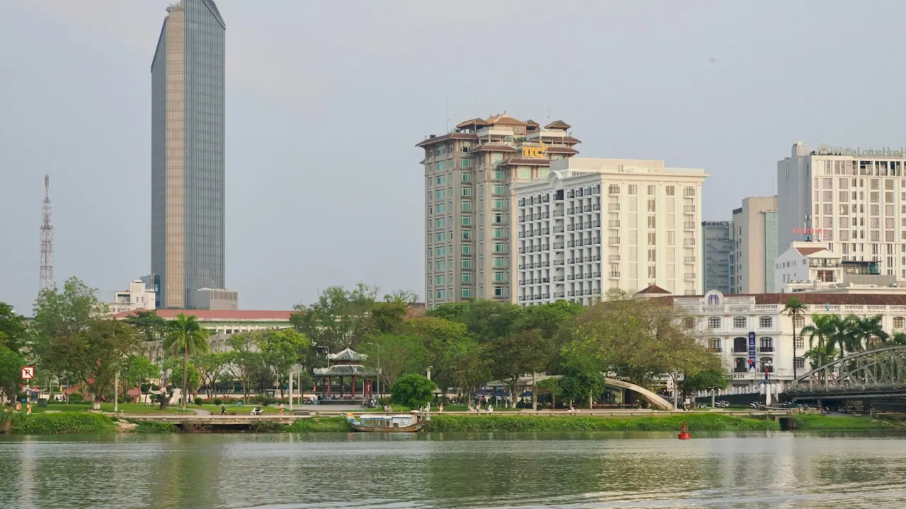 Modern residential towers rising above trees along a calm river