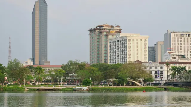 Modern residential towers rising above trees along a calm river