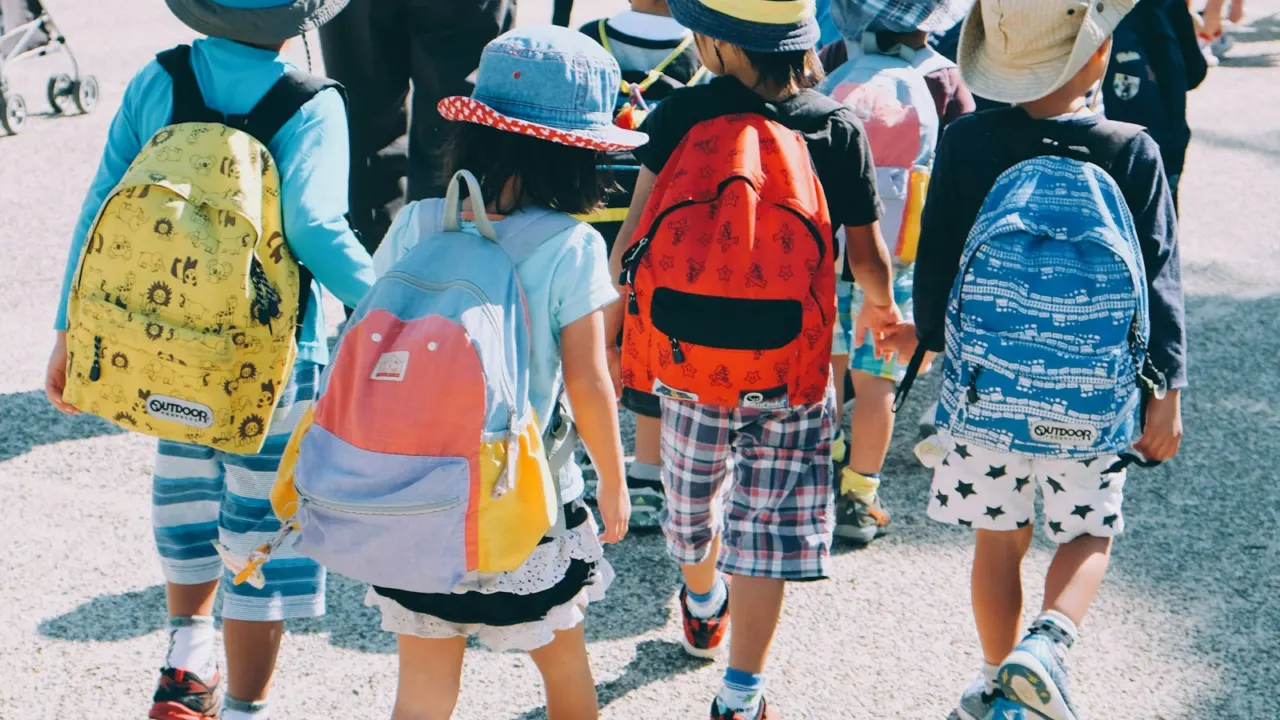 Young children with colourful backpacks and hats walking together on a path