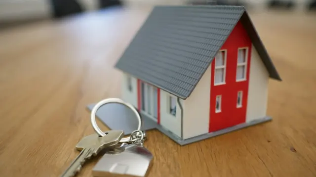 Small model house with a set of keys on a wooden table