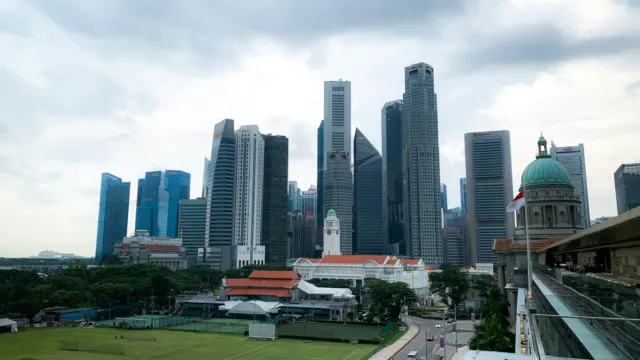 Singapore central business district towers seen across a green field on a cloudy day