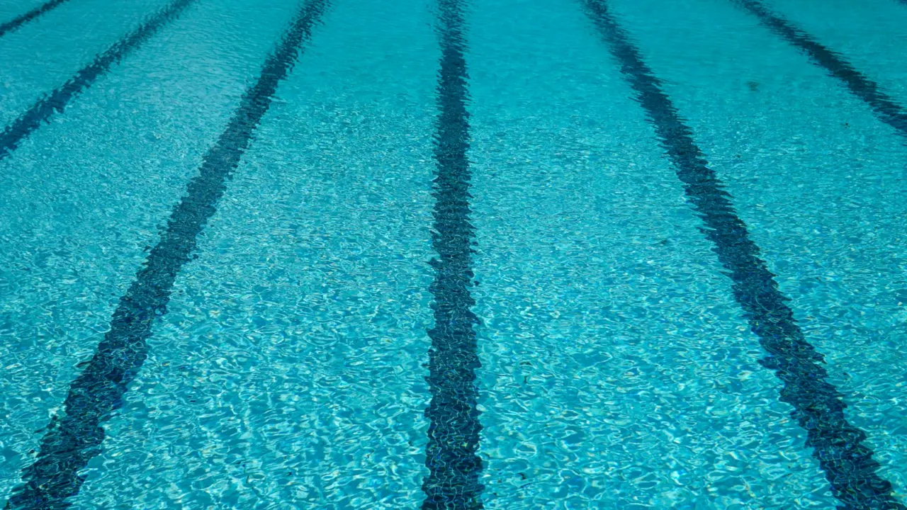 Close-up of dark lane lines on the tiled floor of a blue swimming pool