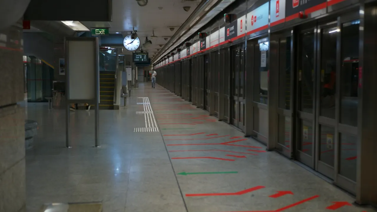 Underground MRT platform with platform screen doors and a commuter walking along it