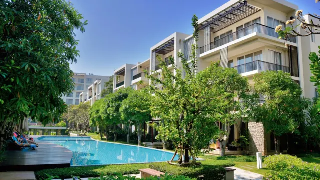 Low-rise condominium blocks with balconies overlooking a swimming pool and trees