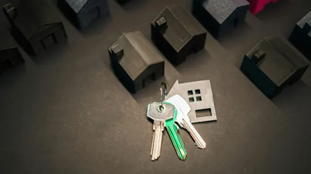一串钥匙和房屋钥匙扣放在一排排小房子模型之间